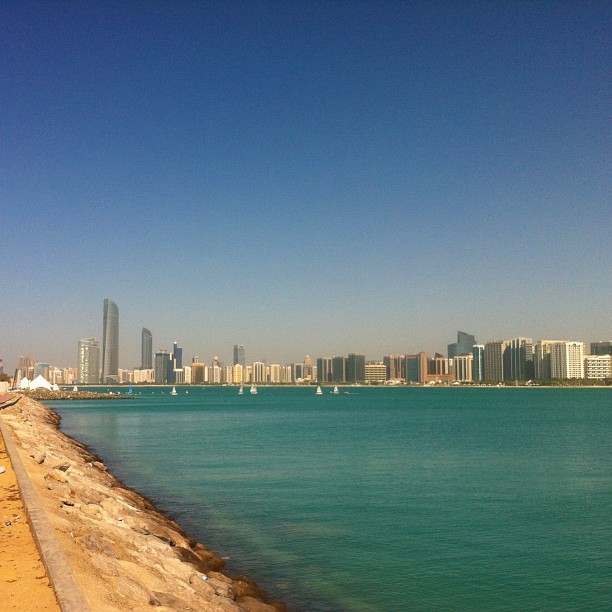 view from the water's edge of an ocean with city in background