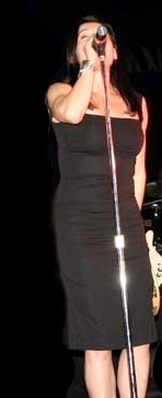 a woman singing with a microphone and a guitar on stage