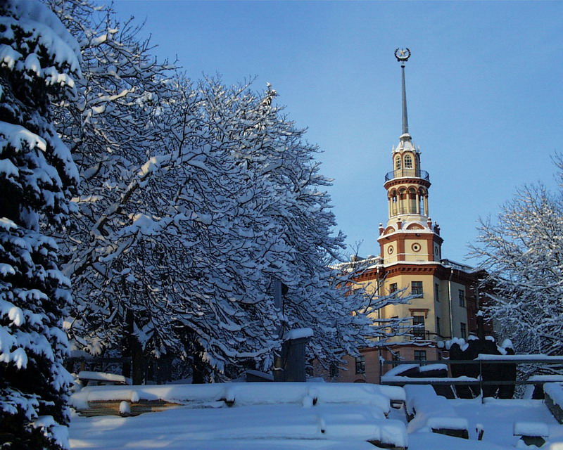 a clock tower stands at the top of a snowy hill