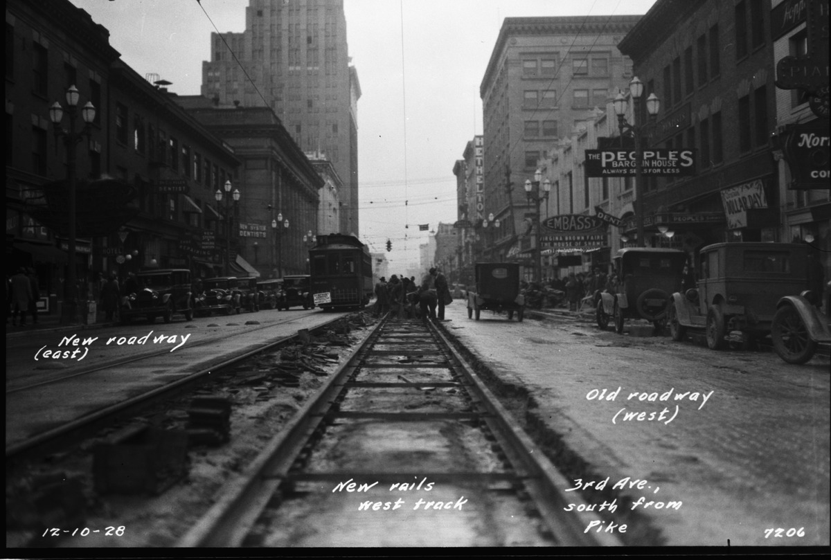 two people walking on the train tracks between two buildings