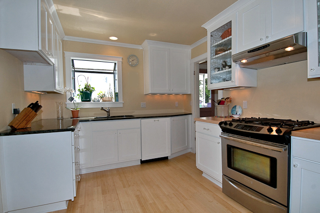 an all white kitchen with white appliances and hardwood floors