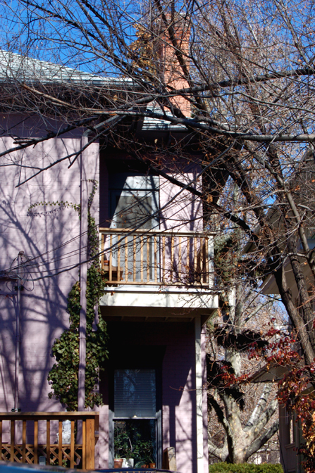 a pink building with lots of windows and a wooden railing