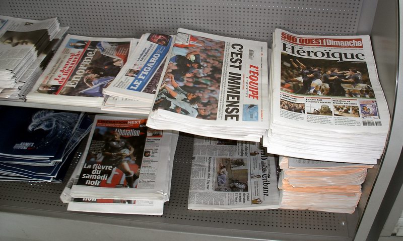 a pile of newspapers on top of a shelf