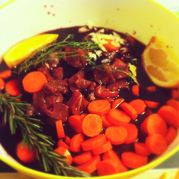 a stew in a white bowl with lemon wedges