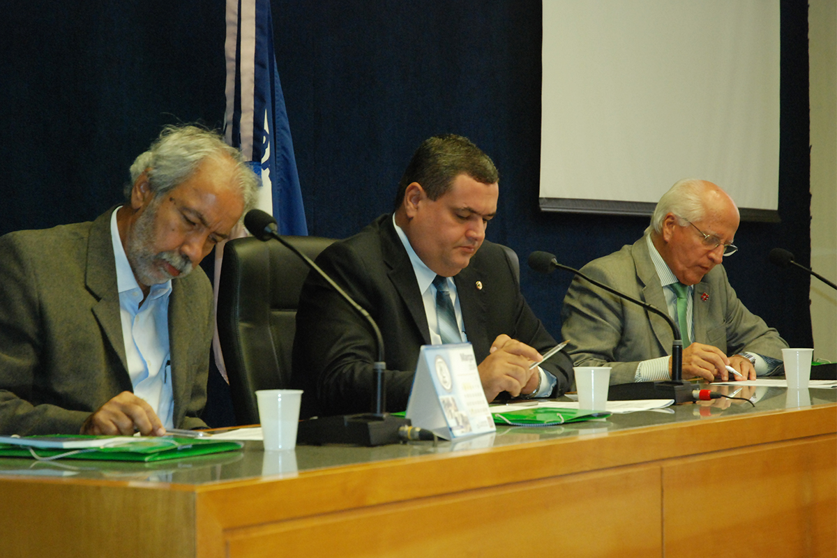 three people sitting in front of a group of microphones at a table