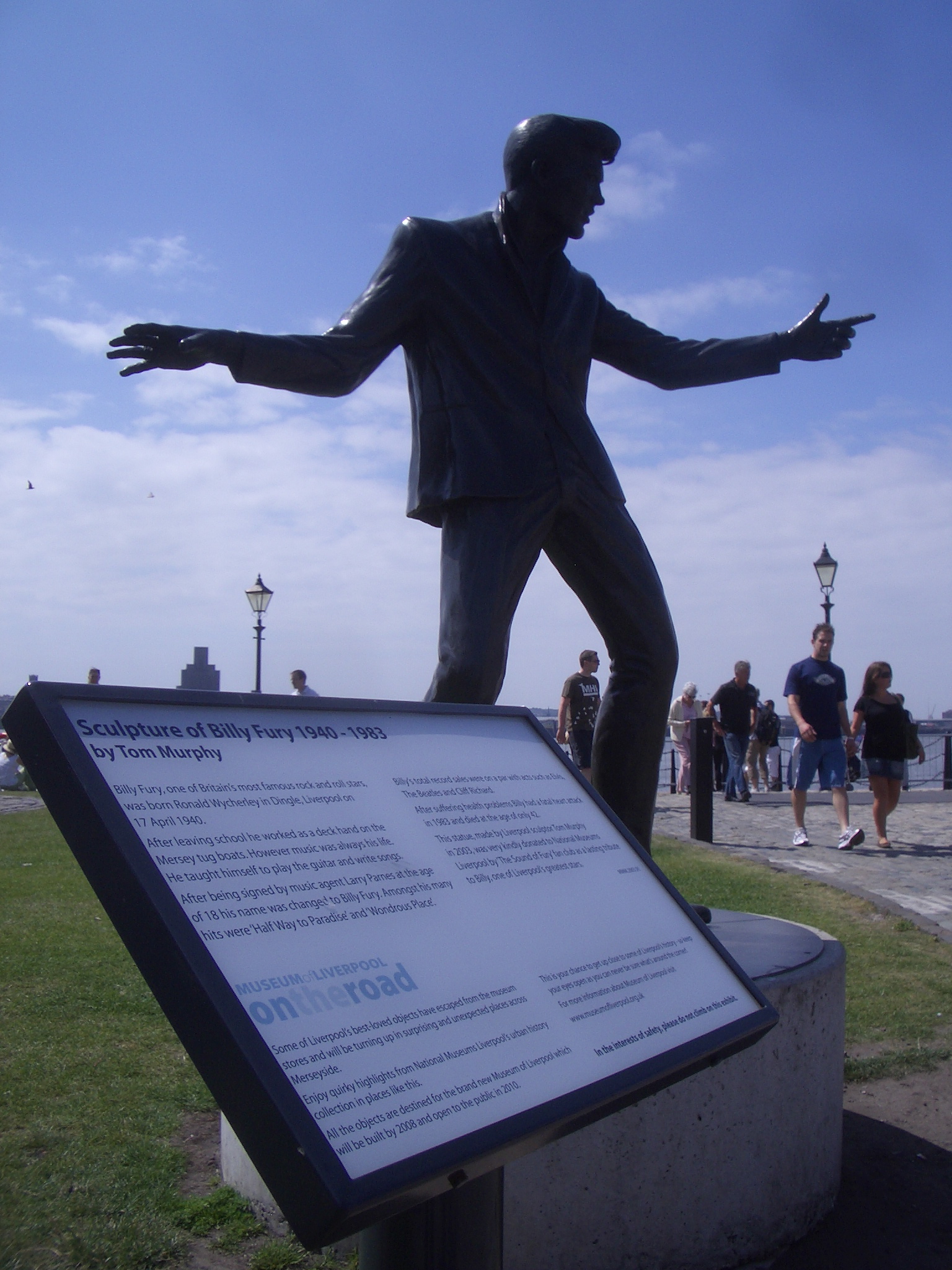 statue of a man with his arms outstretched, standing in front of the water