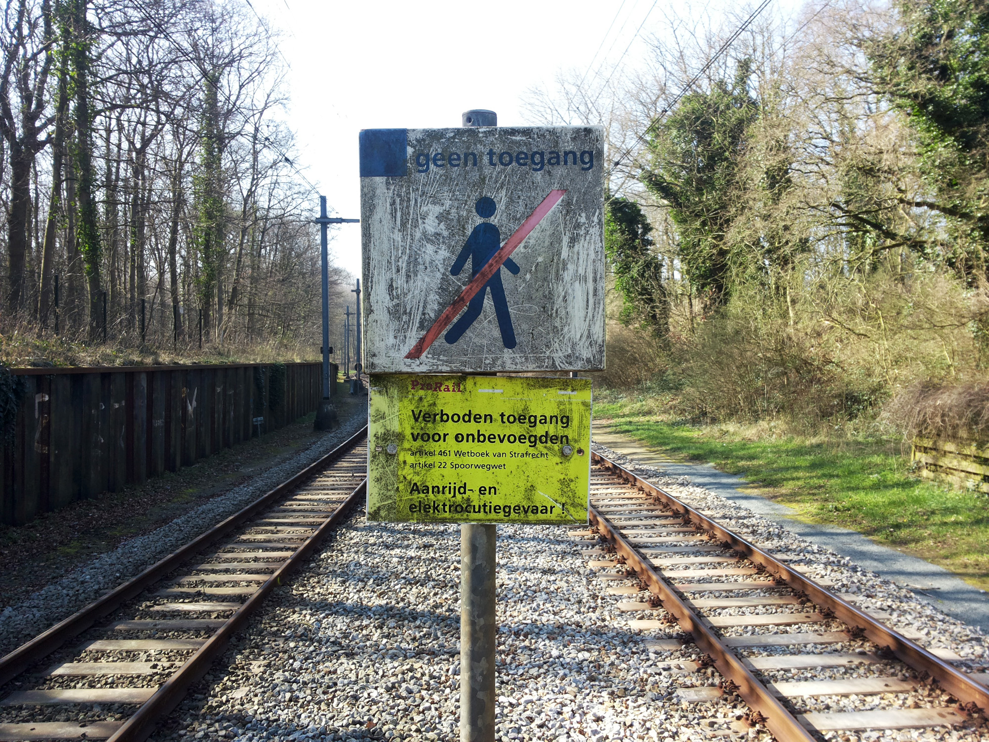 a sign warning of a man standing in front of an railroad crossing