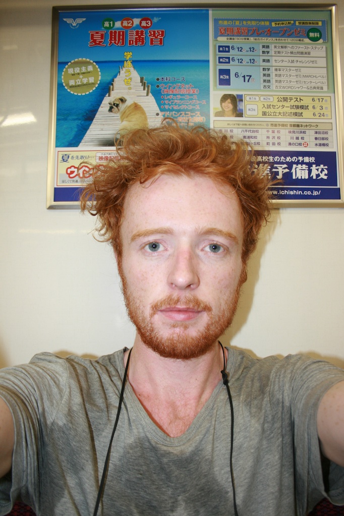 man with red hair and headphones on in front of a chinese menu