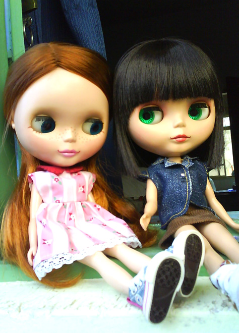 the two dolls are sitting side by side
