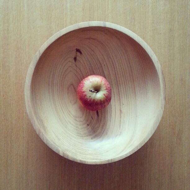 an apple is in a wooden bowl, seen from above