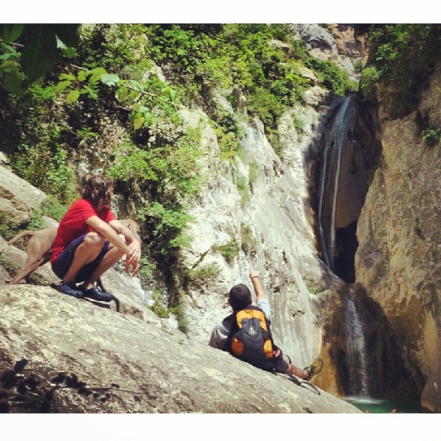 two s are sitting on the rocks overlooking a waterfall