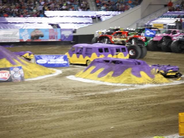 an outdoor arena with big purple vehicles and monster trucks