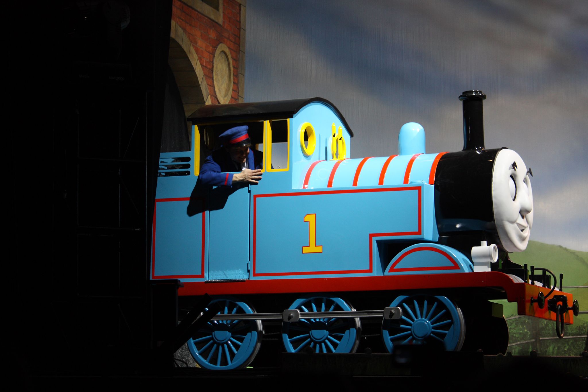 a young child riding on a blue and red thomas the train