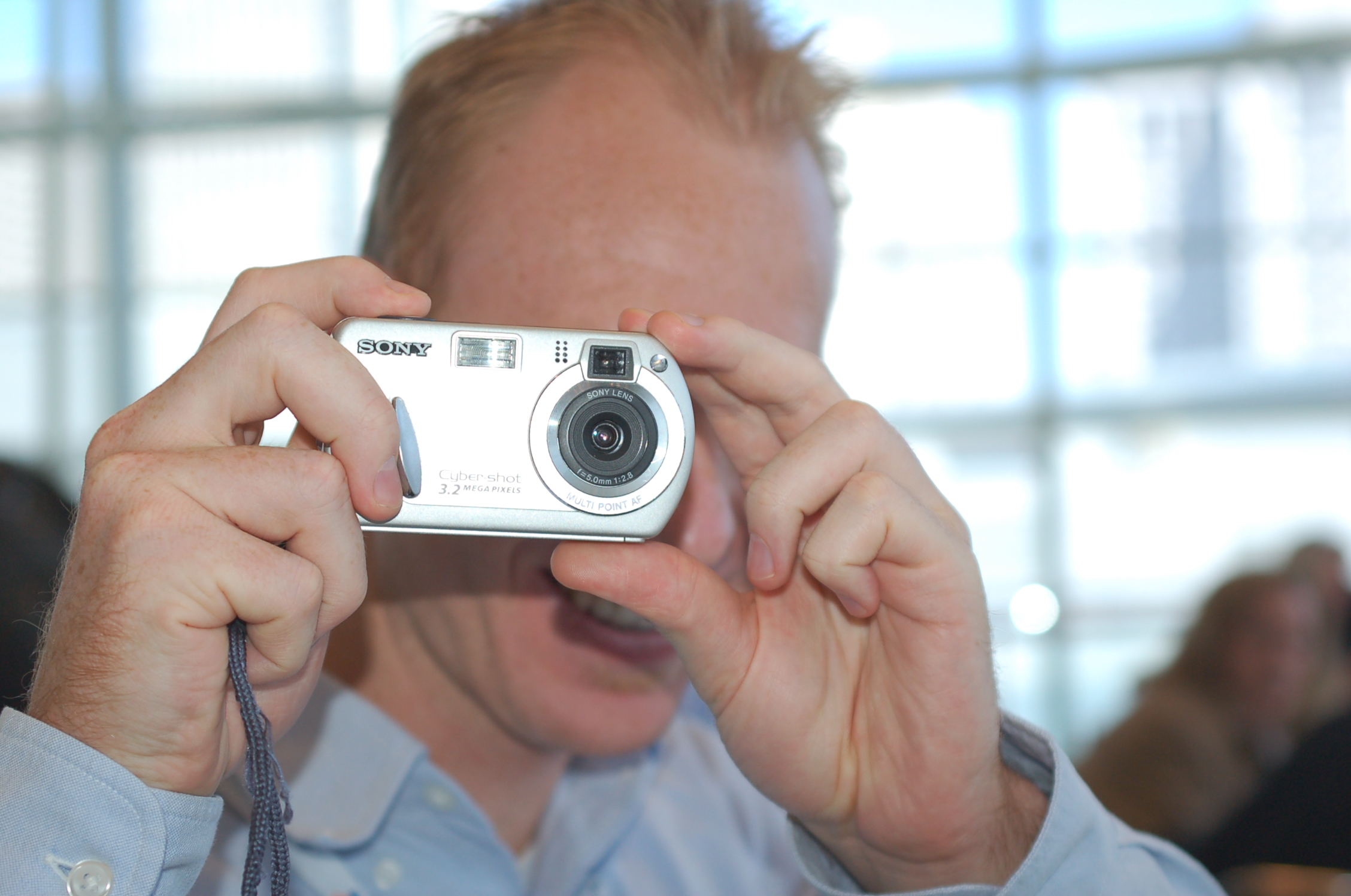 the man holds up his camera in order to take a picture