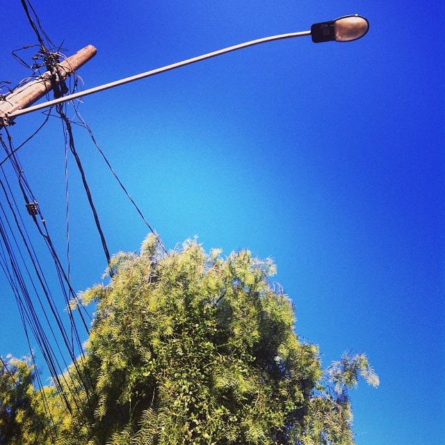 an electrical pole with two wooden power lines, and telephone wires running over it