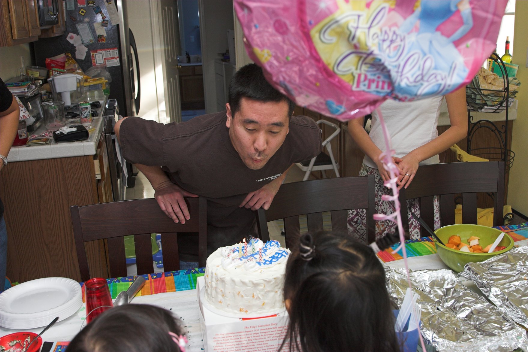 a man blowing out candles on a cake at a table