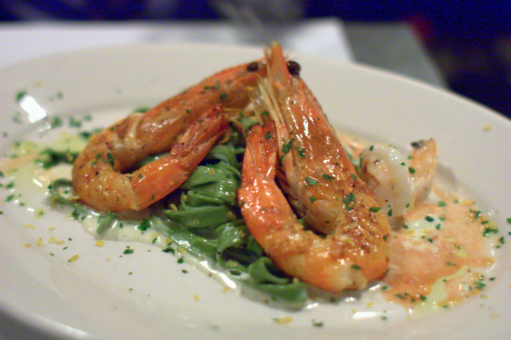 a piece of cooked shrimp sits atop a salad