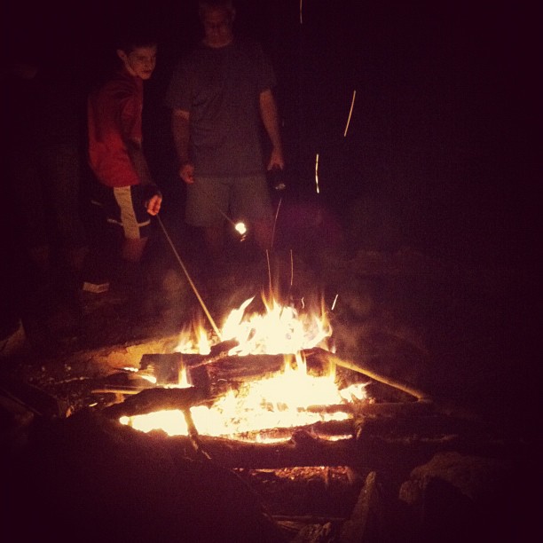 three people watching two torches burning in the dark