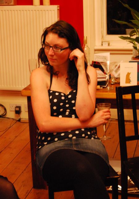 a woman sits on a stool holding her head in one hand