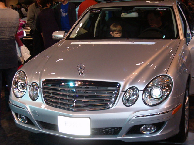 a silver car is in a show room while a crowd looks on