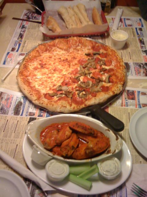 the pizza and a platter of chicken wings on a table