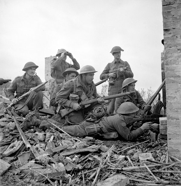 group of soldiers sitting in rubble looking in distance