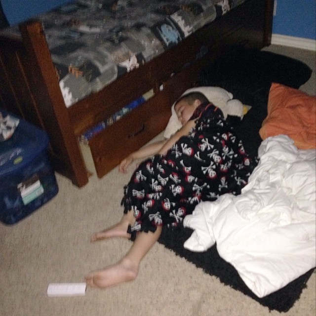a child is laying on the floor by the bunk bed