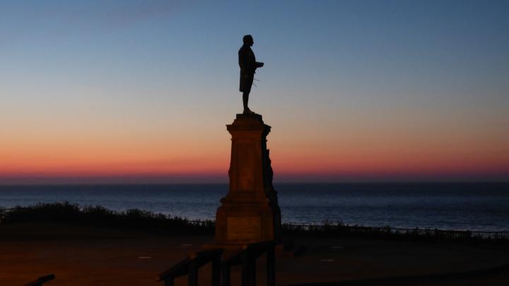 a person is standing on a pedestal overlooking the ocean