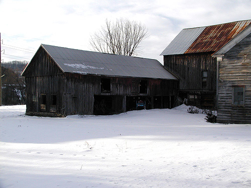 an old barn is surrounded by snow on the farm