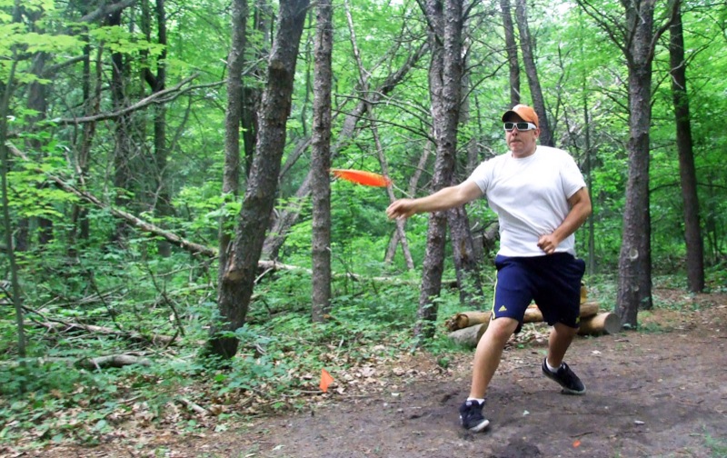 a man in a hat and sunglasses throws a frisbee