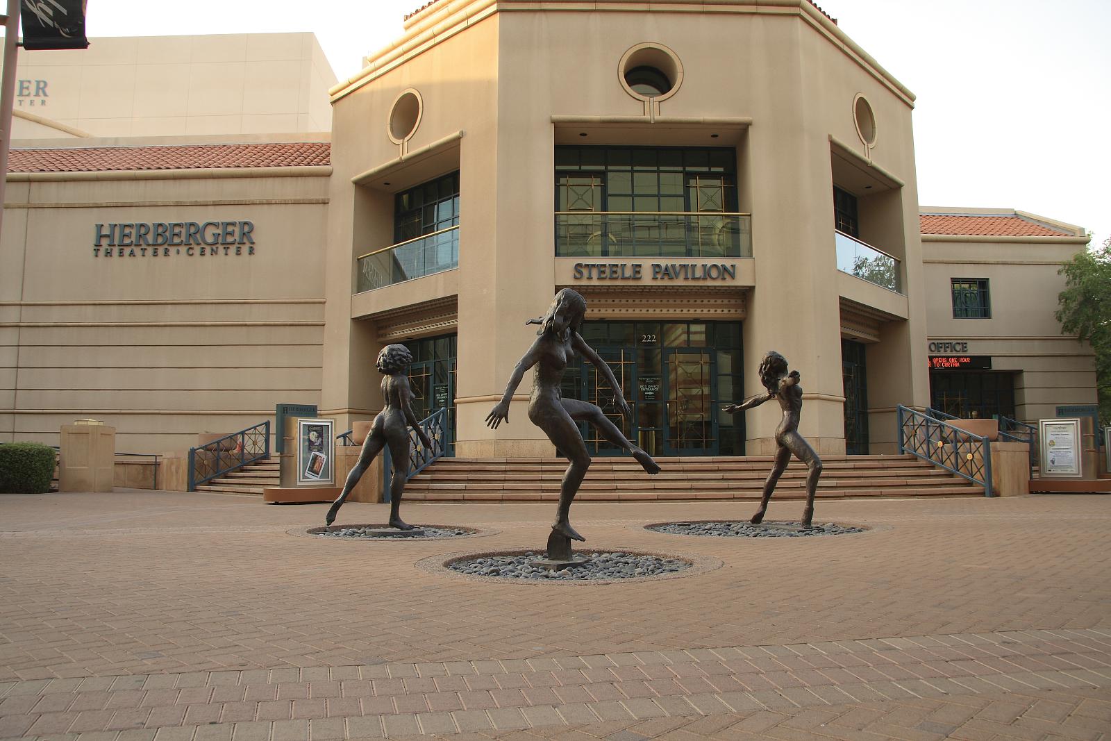 statues of men playing tennis in front of an office