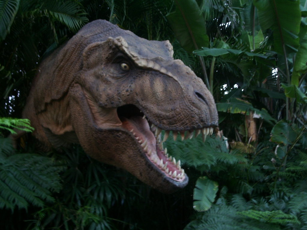 large dinosaur head in some fern plants