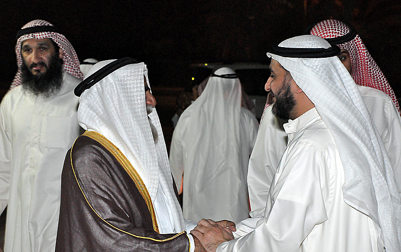 four men dressed in traditional dress shaking hands