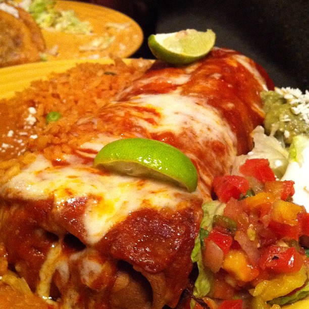 a plate topped with chicken enchilada and mexican rice