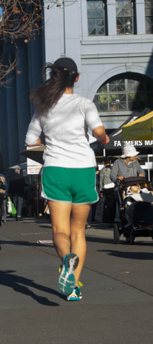 the woman is running down the street in green shorts