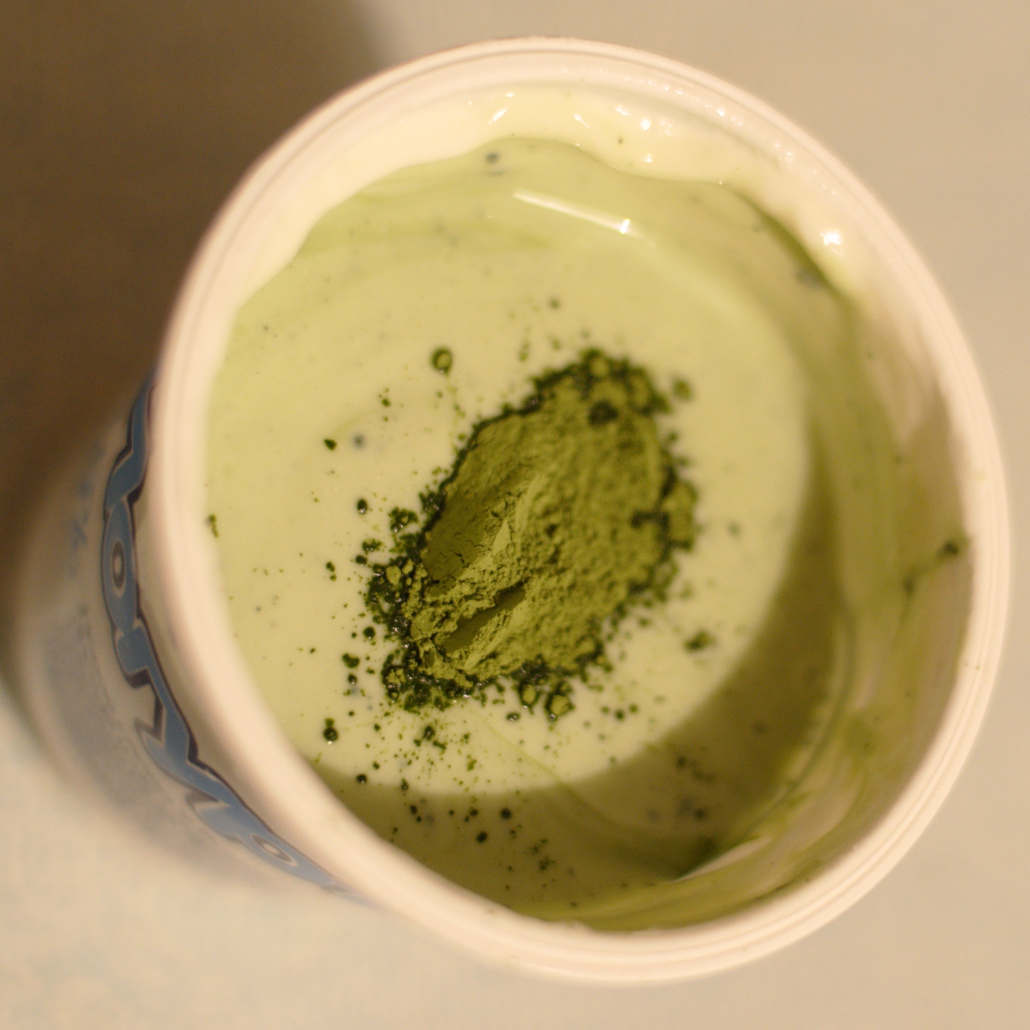 a white cup filled with green stuff and some other things