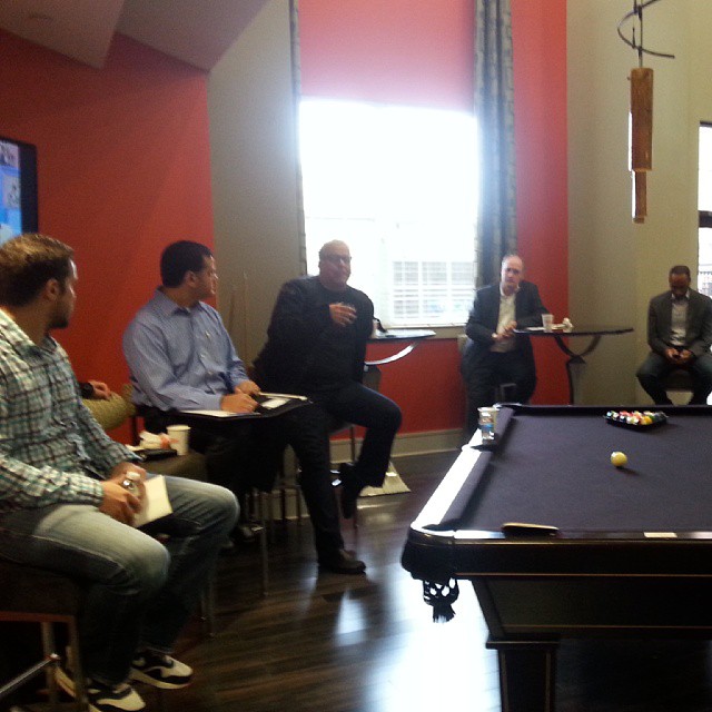 several people sitting around a pool table with food