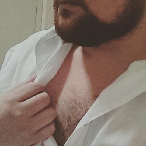 a bearded man with white shirt and beard, adjusting his tie