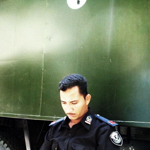a policeman standing next to a green semi