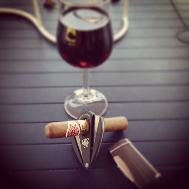 a cigar on a table next to a glass of wine