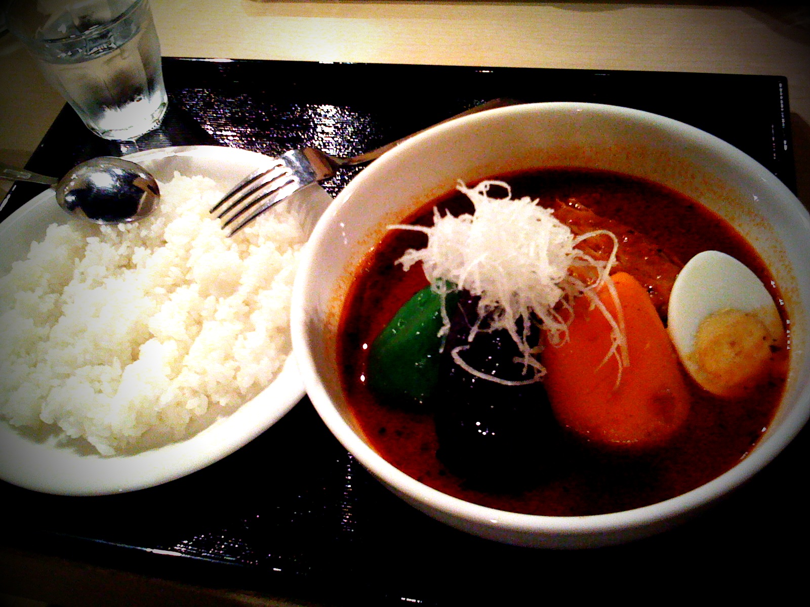 a plate with soup and rice and an egg on the side