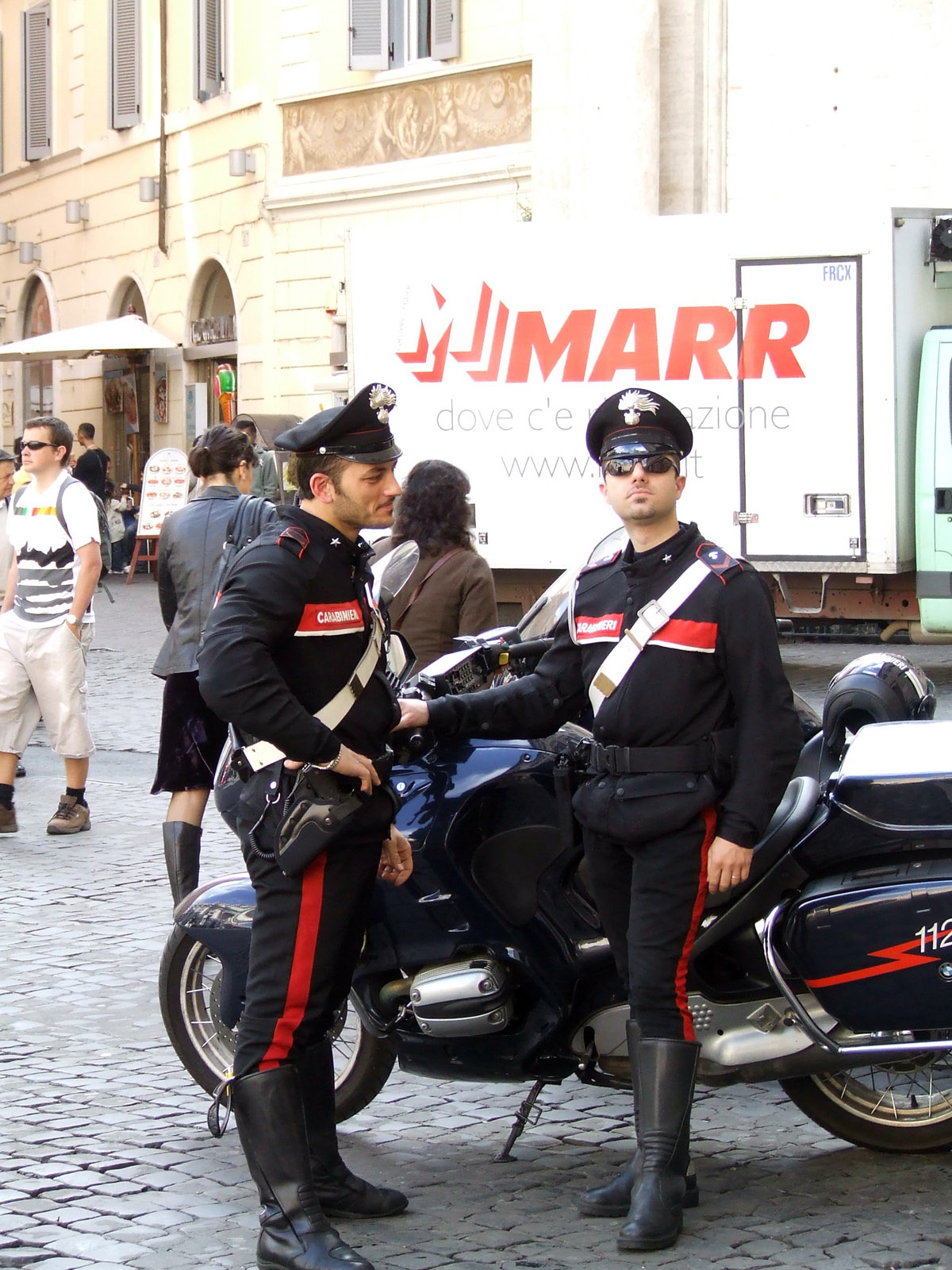 two men in military clothes standing next to a motorcycle