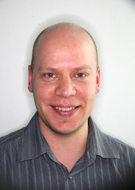 a bald man in striped shirt looking directly into the camera