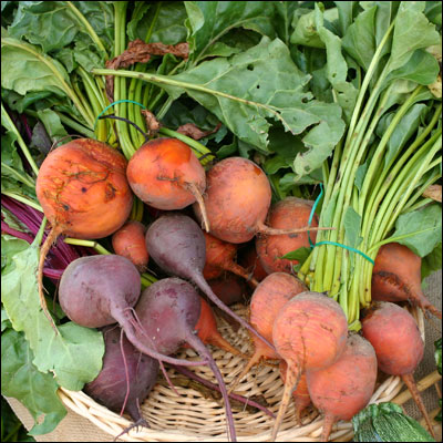 some carrots and other vegetables sitting in a wicker basket