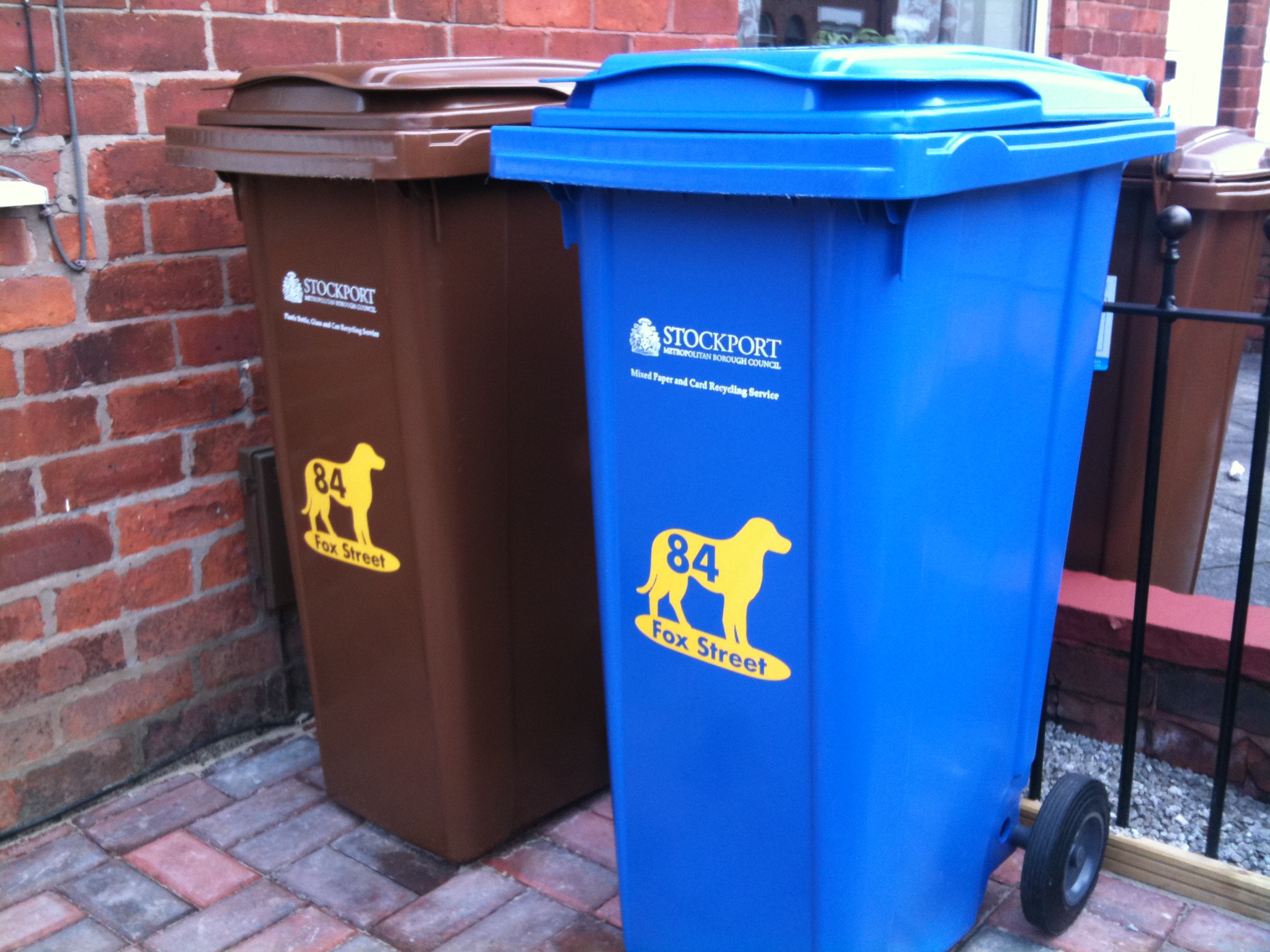 two trash cans are sitting beside each other on the side walk