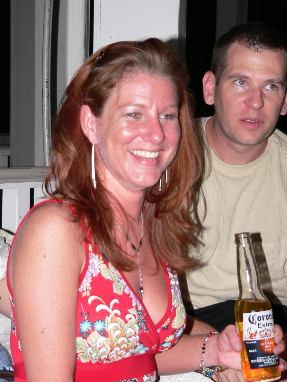 a young couple sitting in a chair together with a beer