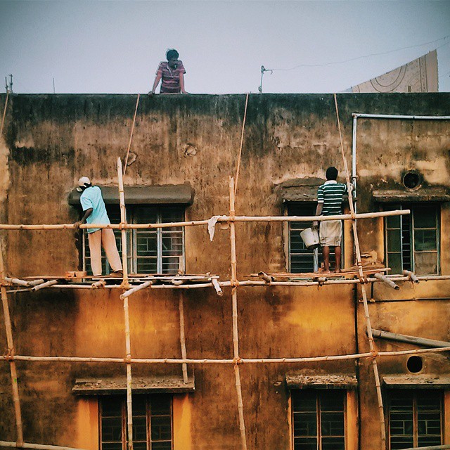 three men standing on a roof on top of the house