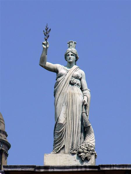 statue with hands raised holding a plant in front of blue sky