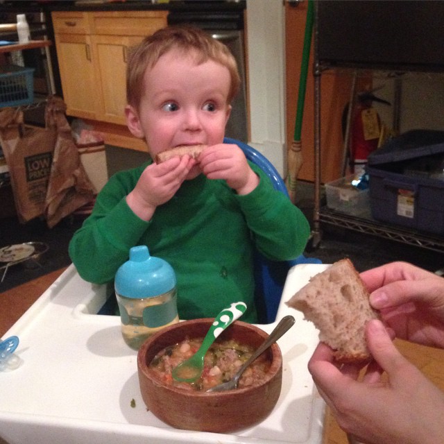 the boy is enjoying his lunch while being held close by his mom