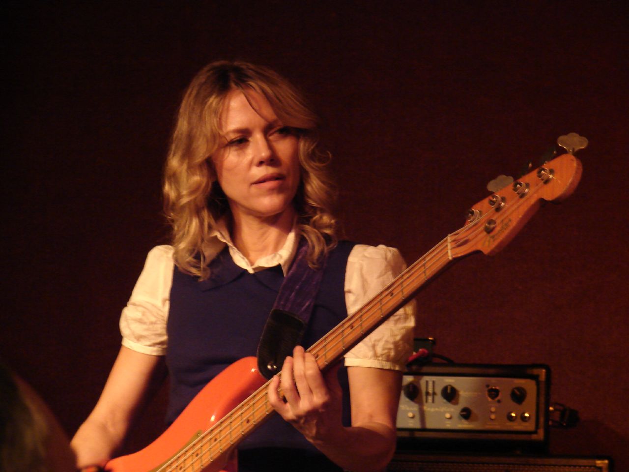 a woman with long hair holding an orange and yellow guitar